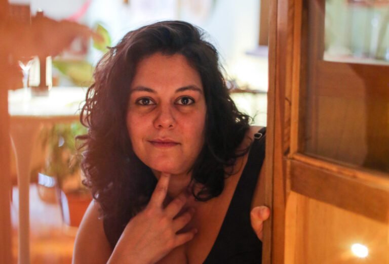 Fernanda Saad olhando através de uma porta, simbolizando o autoconhecimento, a importância de não de conformar e a busca por propósito e satisfação no trabalho.